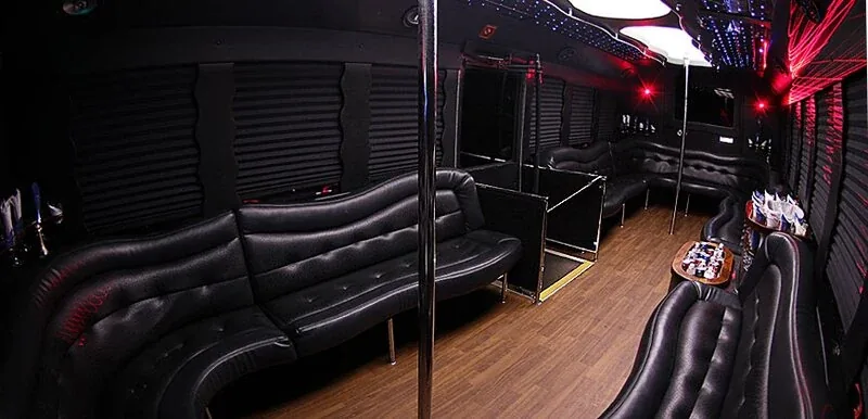 Black leather party bus interior with wraparound seating and colored lighting for a Los Angeles night out